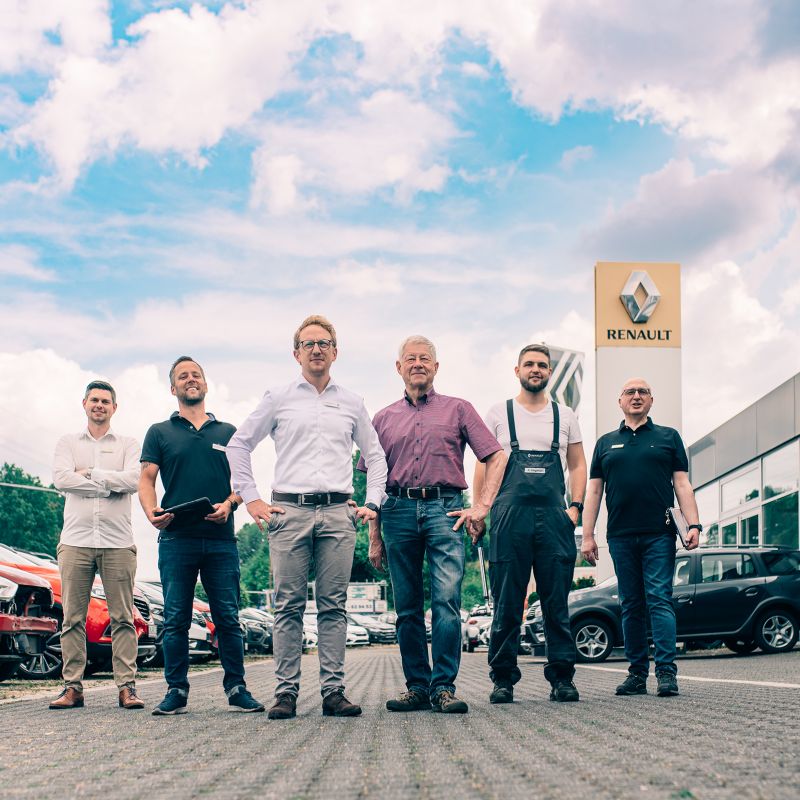 Mehrere Mitarbeiter stehen vor einem Autohaus