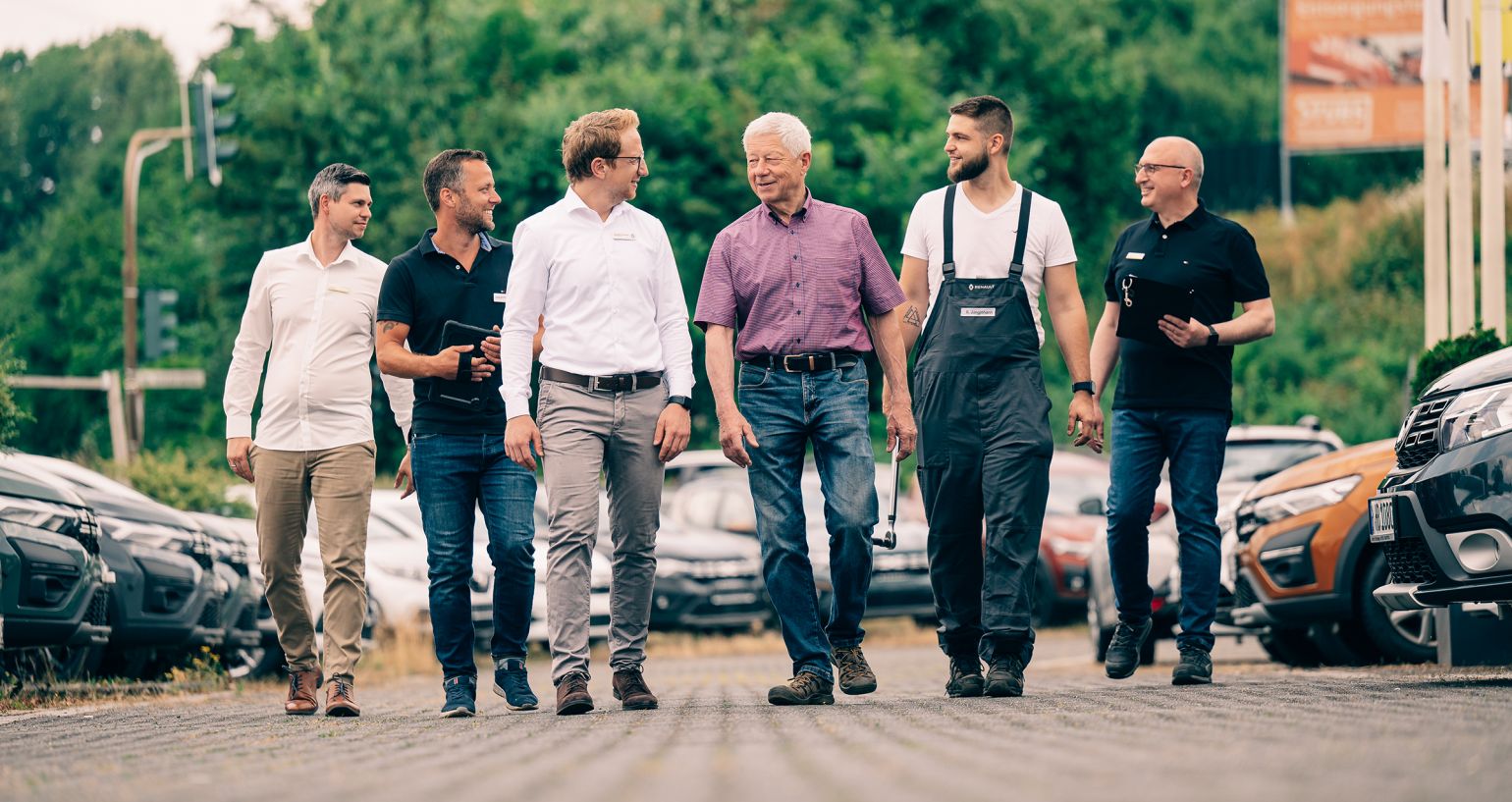 Mehrere Mitarbeiter gehen gemeinsam über einen Parkplatz mit Autos im Hintergrund