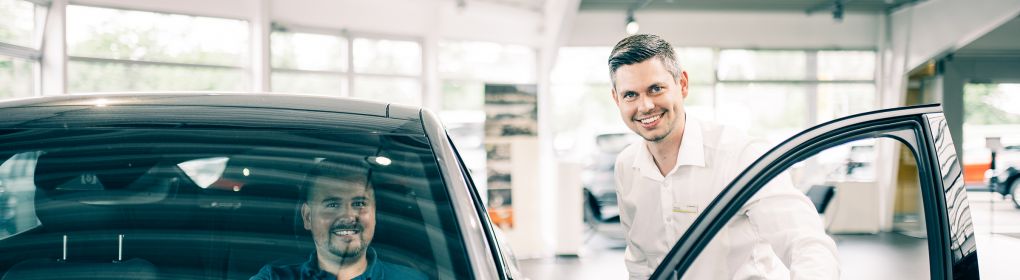 Kunde sitzt im Auto während ein Mitarbeiter die Tür öffnet