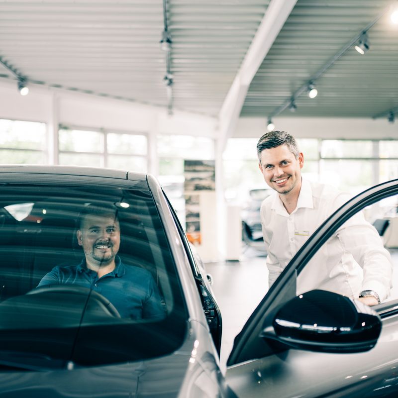 Kunde sitzt im Auto während ein Mitarbeiter die Tür öffnet